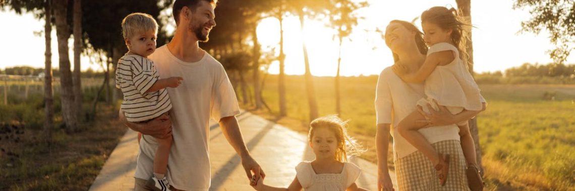 A joyful family walking together on a sunlit path during sunset, enjoying an outdoor stroll.