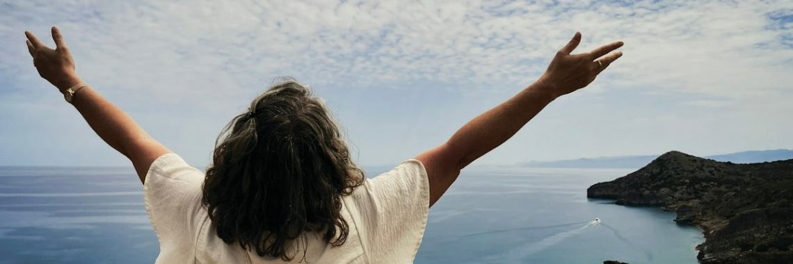 Woman with arms outstretched overlooking the ocean